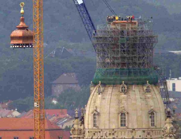 Žerjav dvigne bakreno kupolo in zlati križ na vrh rekonstruirane Frauenkirche v Dresdnu, Nemčija