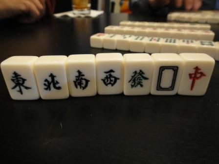 Vetrovi in ​​zmaji ploščice v mahjongski garnituri, ki stojijo pokonci na mizi.