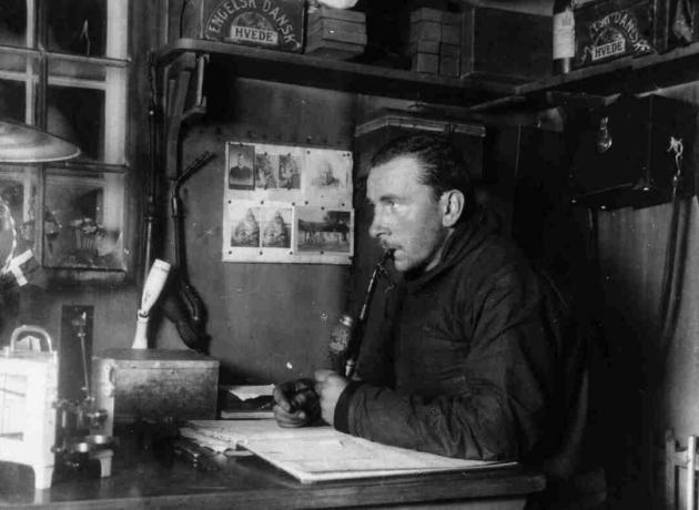 Alfred Wegener, ki dela za svojo mizo, črno-belo fotografijo.