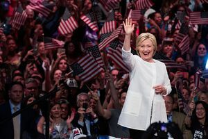 Hillary Clinton maha pred množico ljudi, ki mahajo ameriškim zastavam