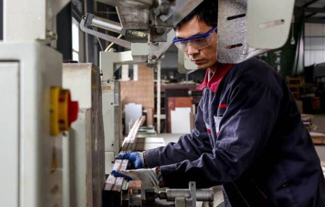 Zaposlen, ki dela na aluminijastih izdelkih v tovarni v Zoupingu v vzhodni kitajski provinci Shandong